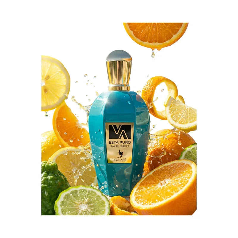 Parfum Volare Esta Puro dans un flacon bleu entouré de tranches d'agrumes et d'éclats d'eau.