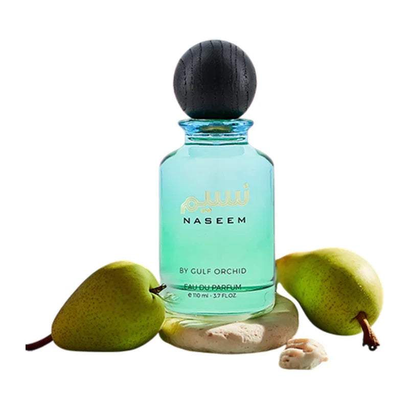 Flacon de parfum NASEEM By Gulf Orchid entouré de poires fraîches sur fond blanc.