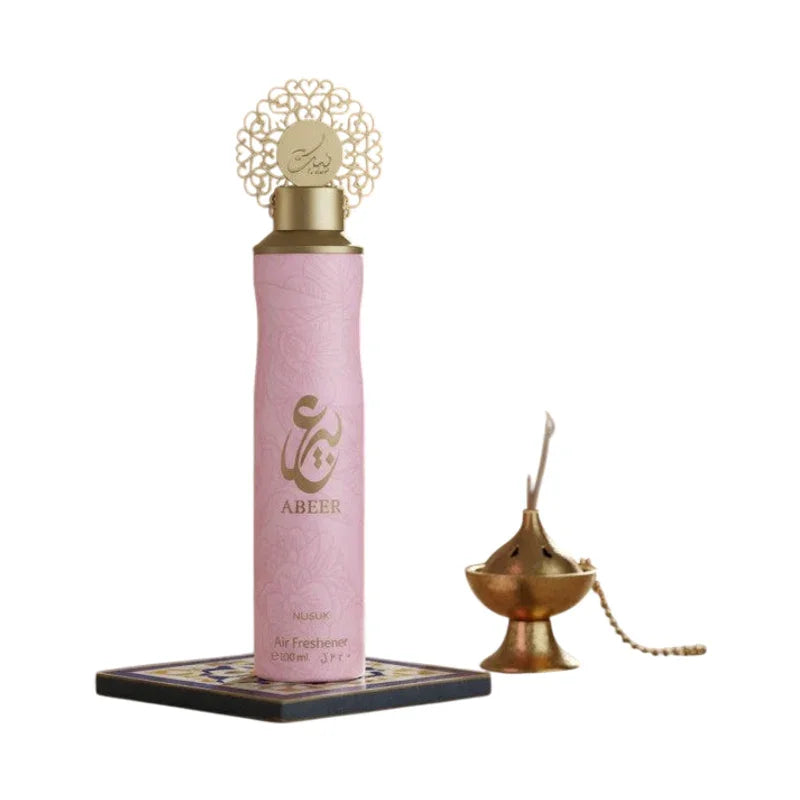 Désodorisant aérien rose Abeer Nusuk avec bouchon doré ornementé sur socle décoratif.