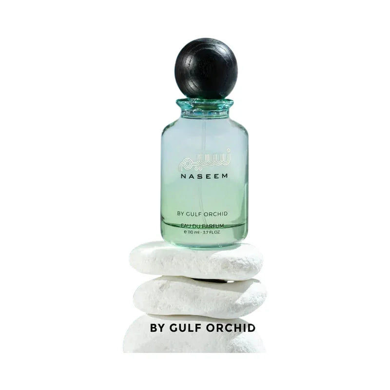 Flacon de parfum Naseem de Gulf Orchid posé sur des pierres blanches