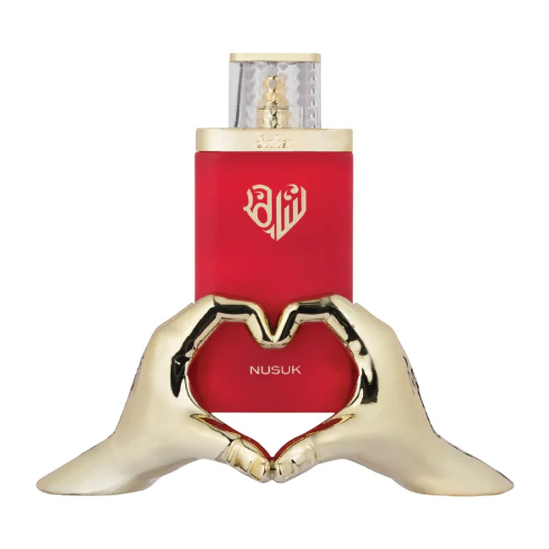 Flacon de parfum rouge Nusuk présenté dans un support décoratif doré en forme de cœur